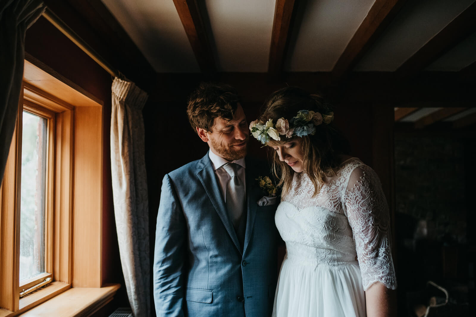 Moody portrait of groom looking at bride in front of window at Shropshire wedding