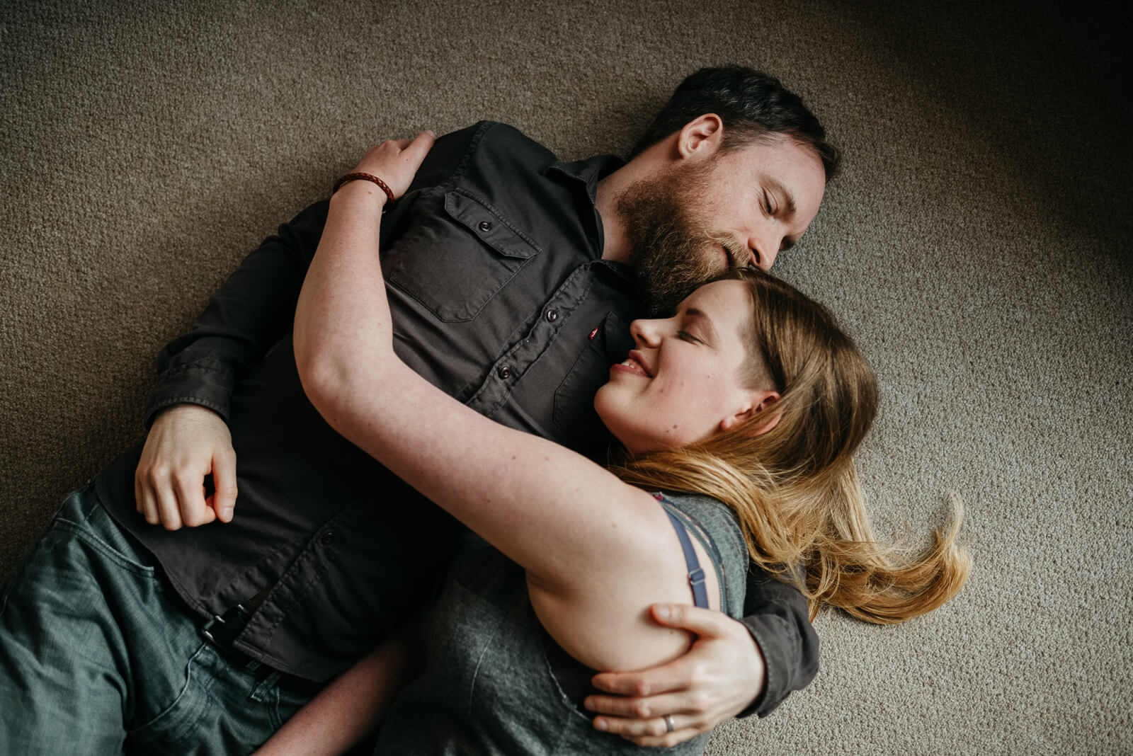 couple lying on floor cuddling during at home couple session