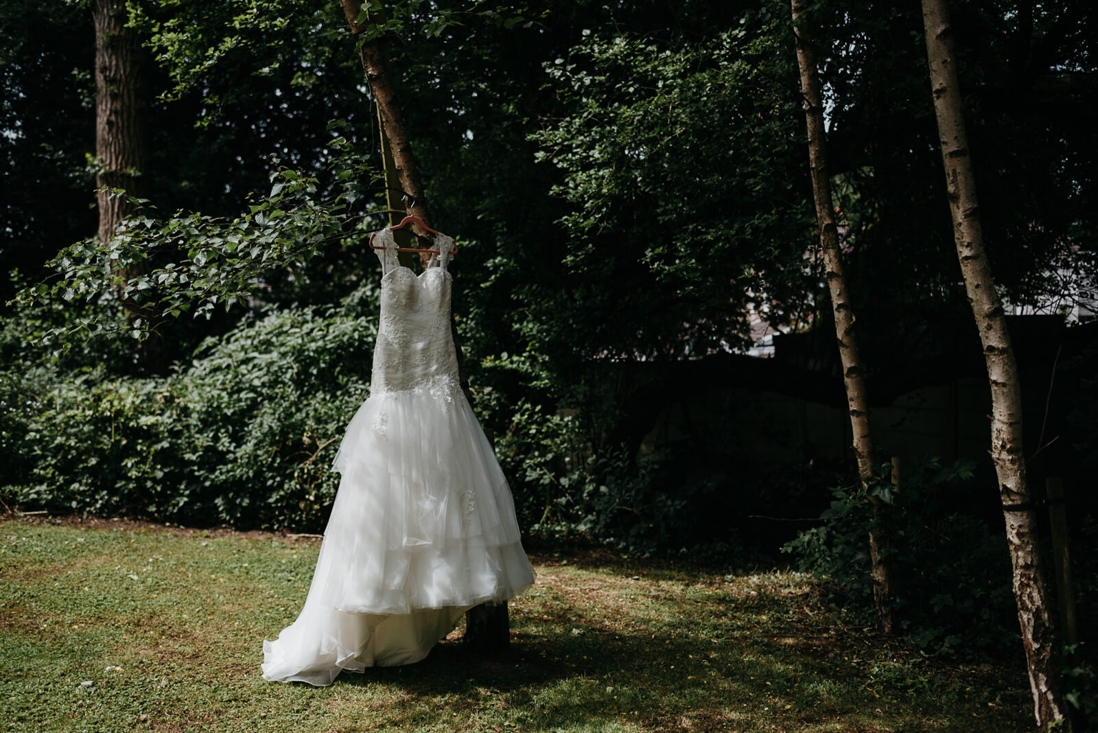 brides dress hanging from tree before her modern intimate city hall wedding