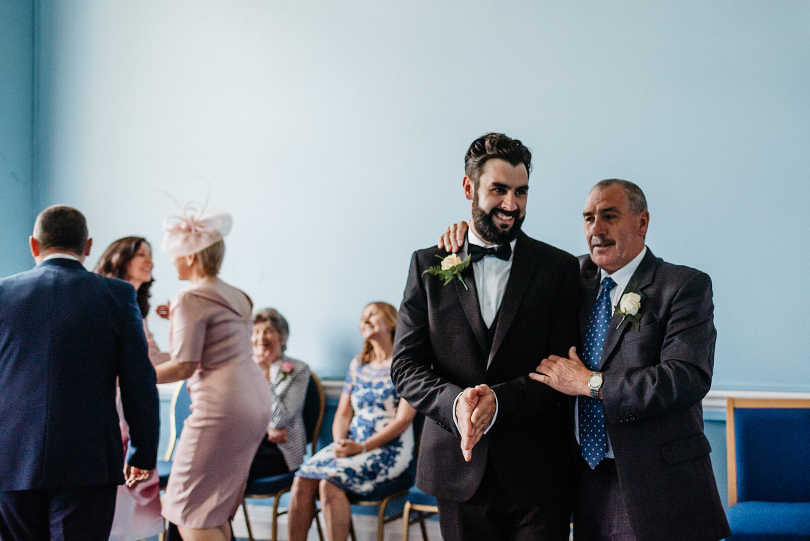 groom and his father share a joke inside city hall wedding venue