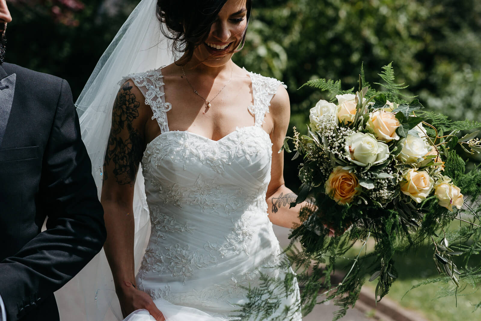 candid photo of radiant tattooed bride walking with her groom