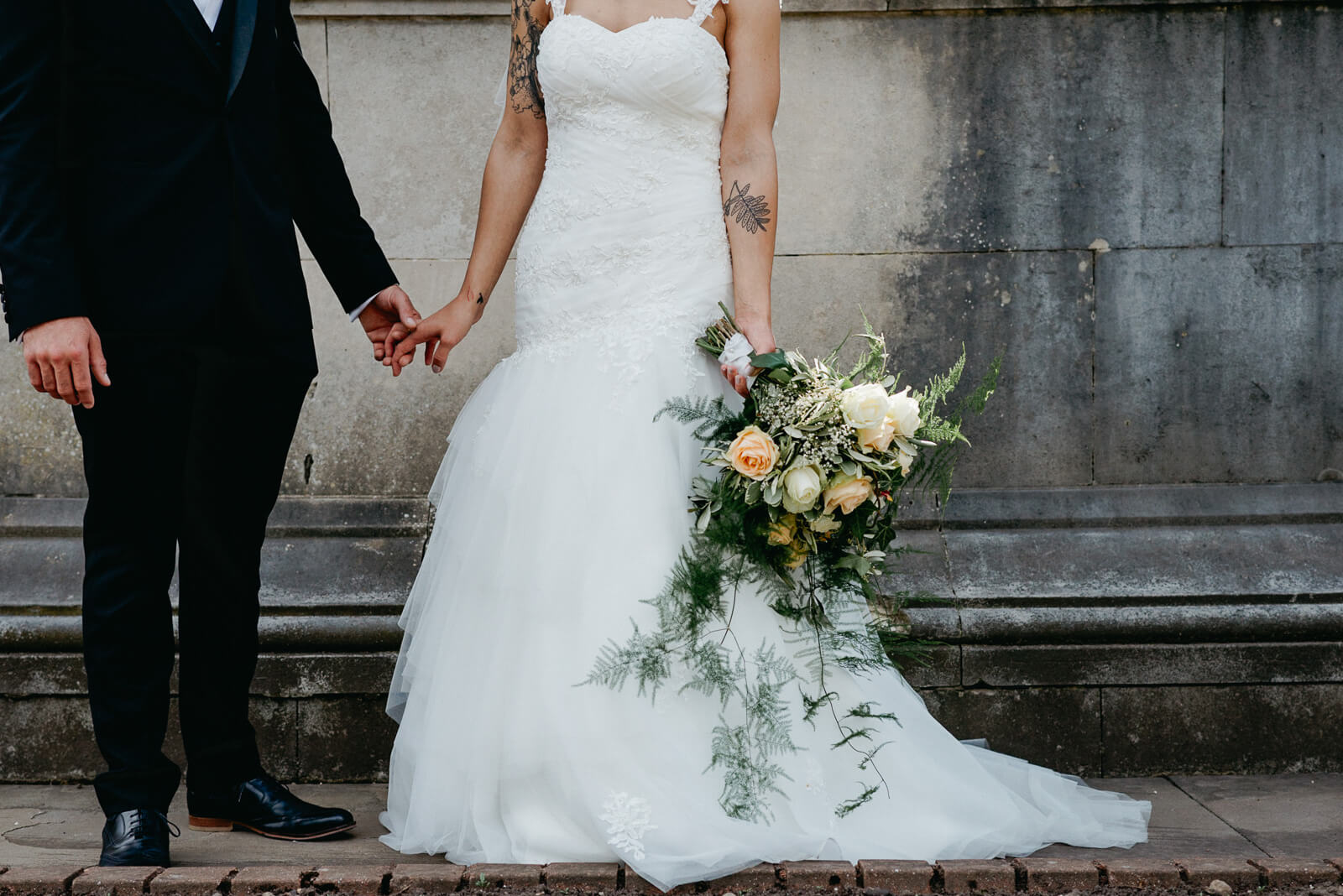 alternative photo of bride and groom holding hands and her bouquet after their city wedding