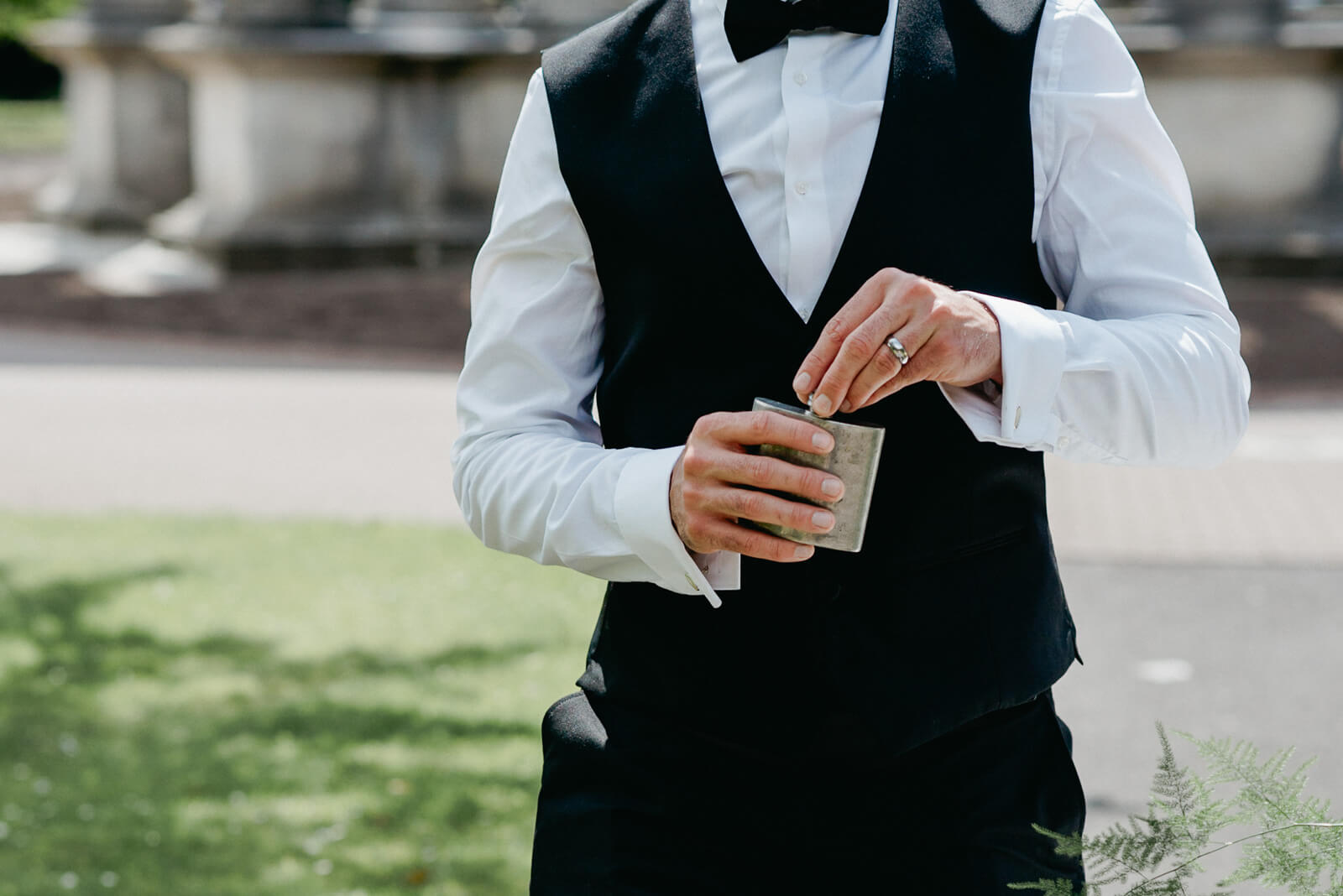 groom taking a drink from his hipflask following their urban wedding ceremony in cardiff