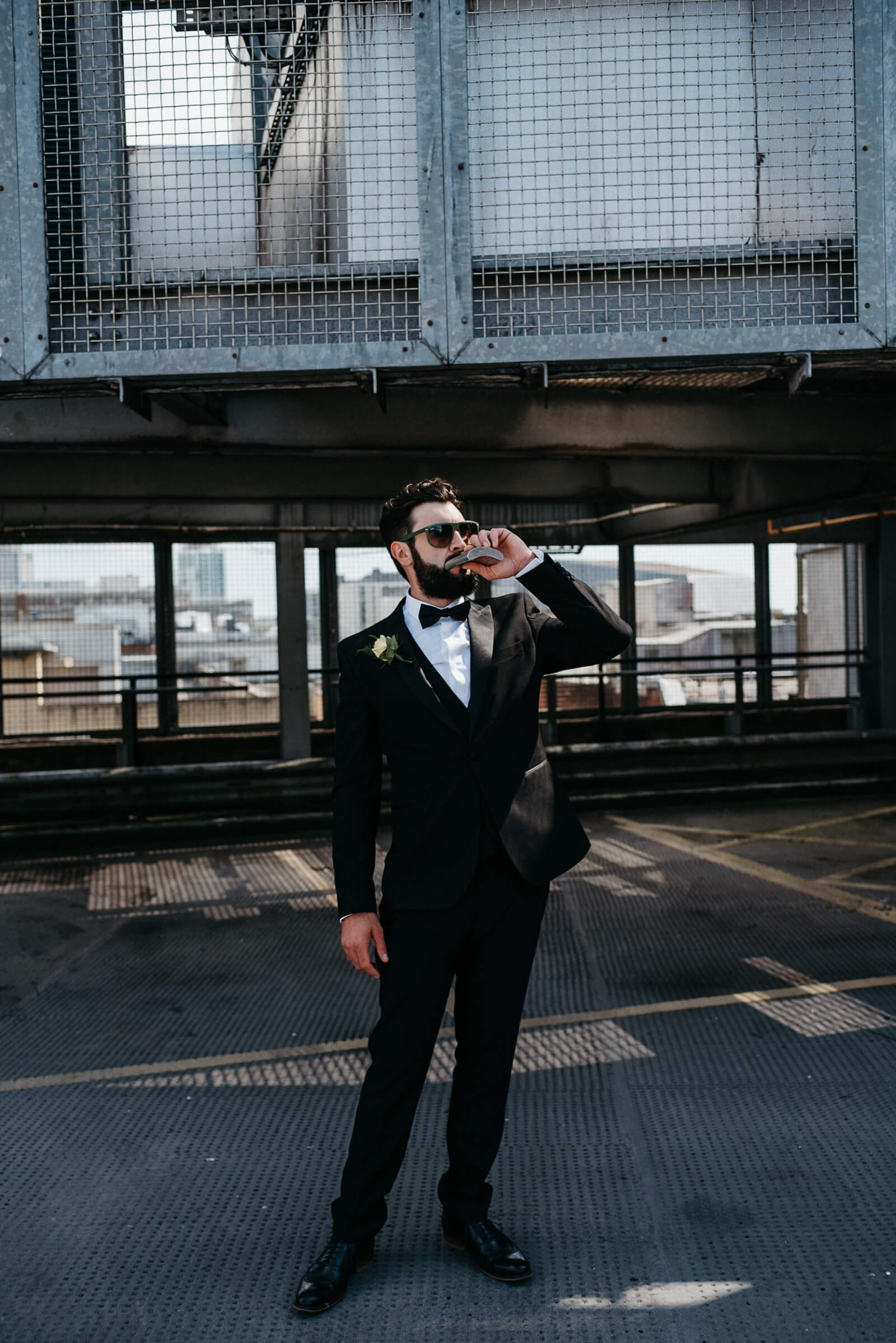 alternative groom in black tie drinking from his hip flask