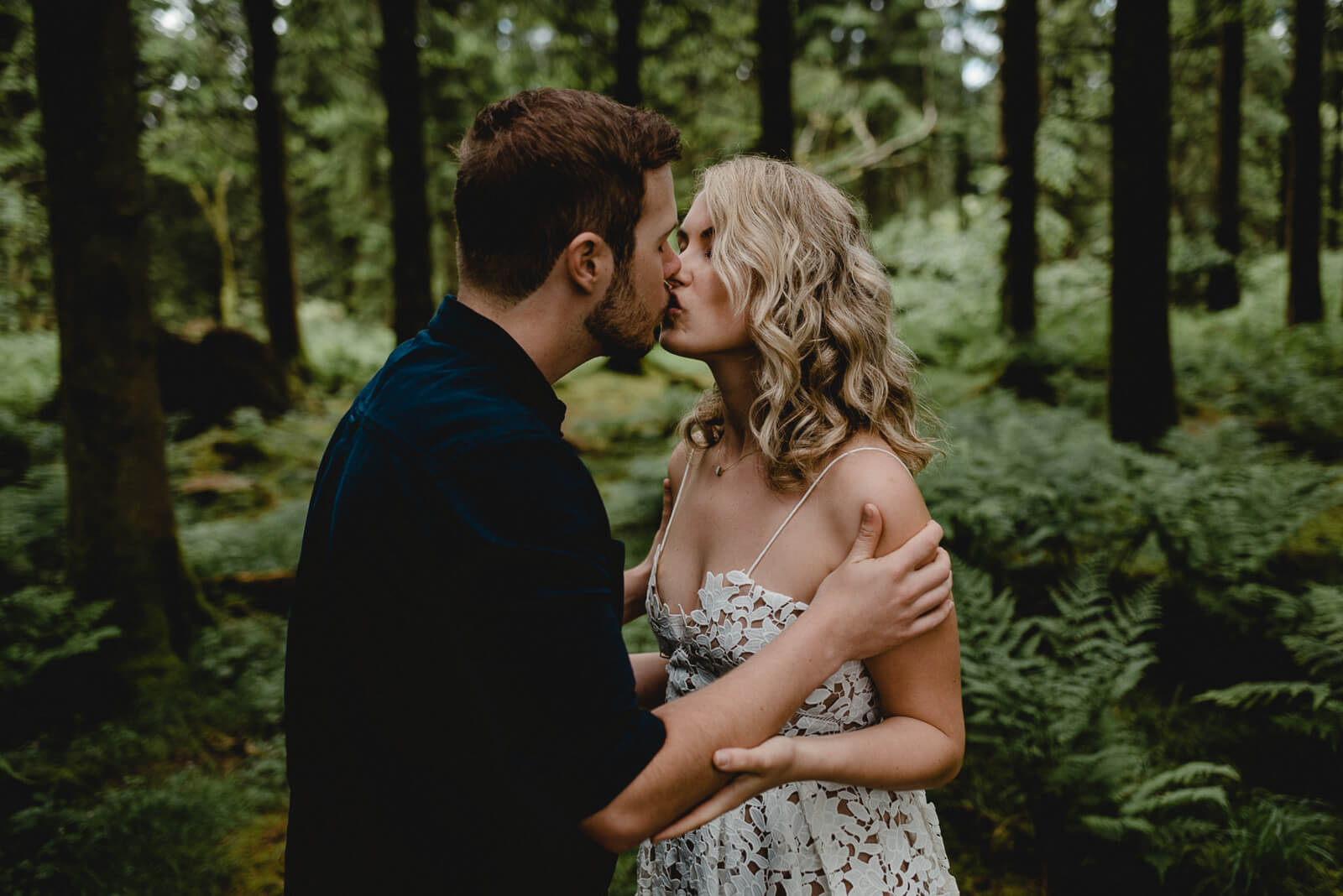bride and groom kissing during woodland portraits