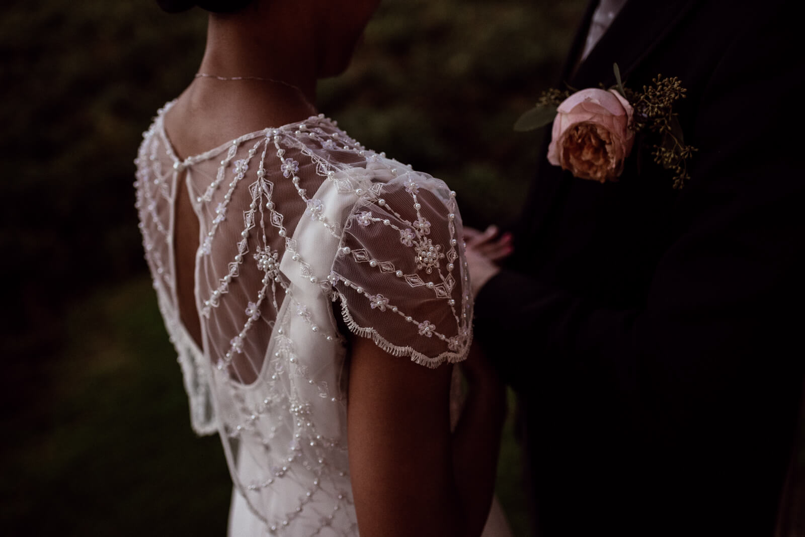 moody detail photograph showing the beading on the brides lace cape 