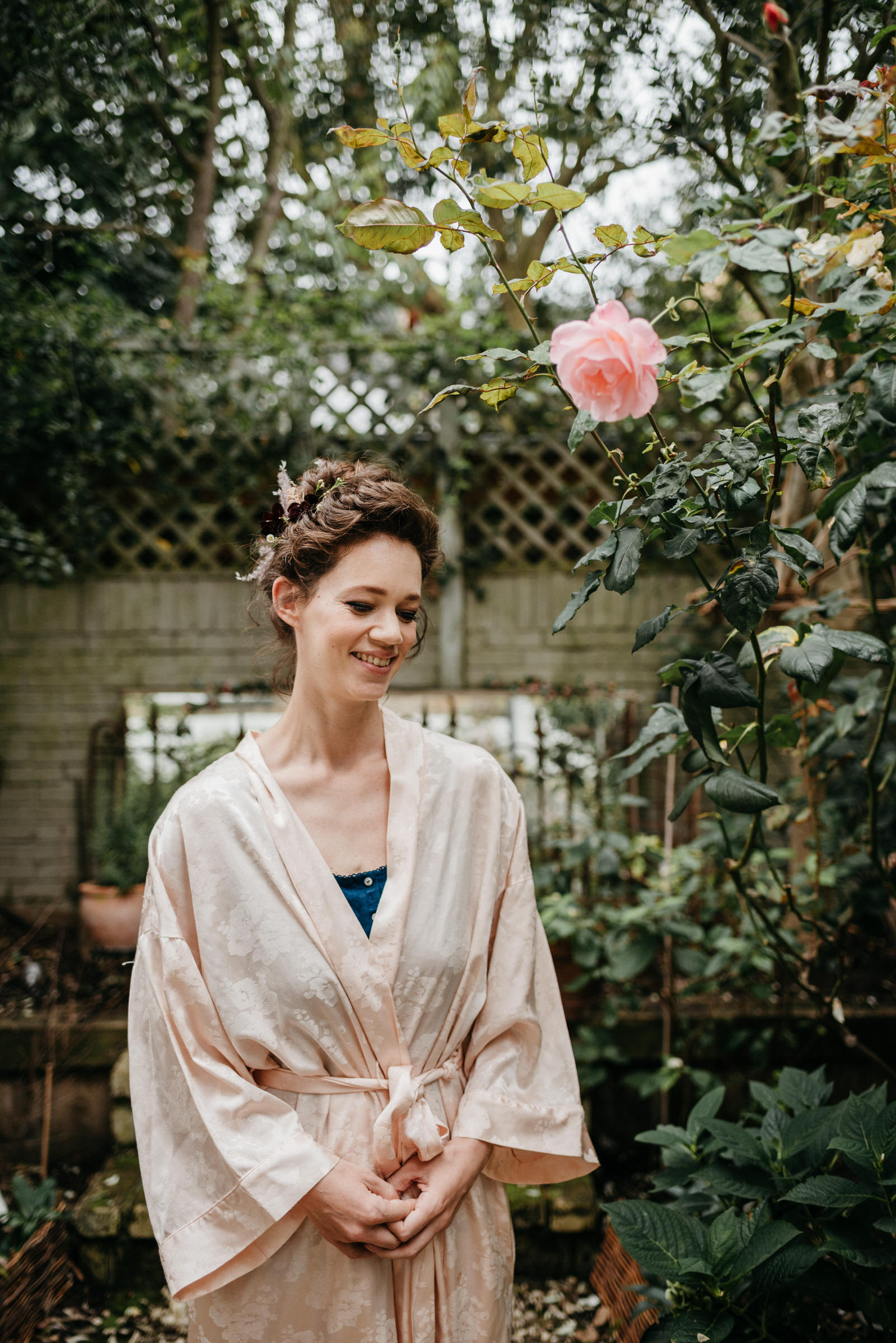 portrait of London bride in garden with pale pink rose wearing pale pink kimono