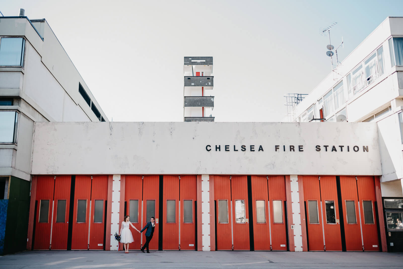 Bride and groom stand outside Chelsea Fire Station