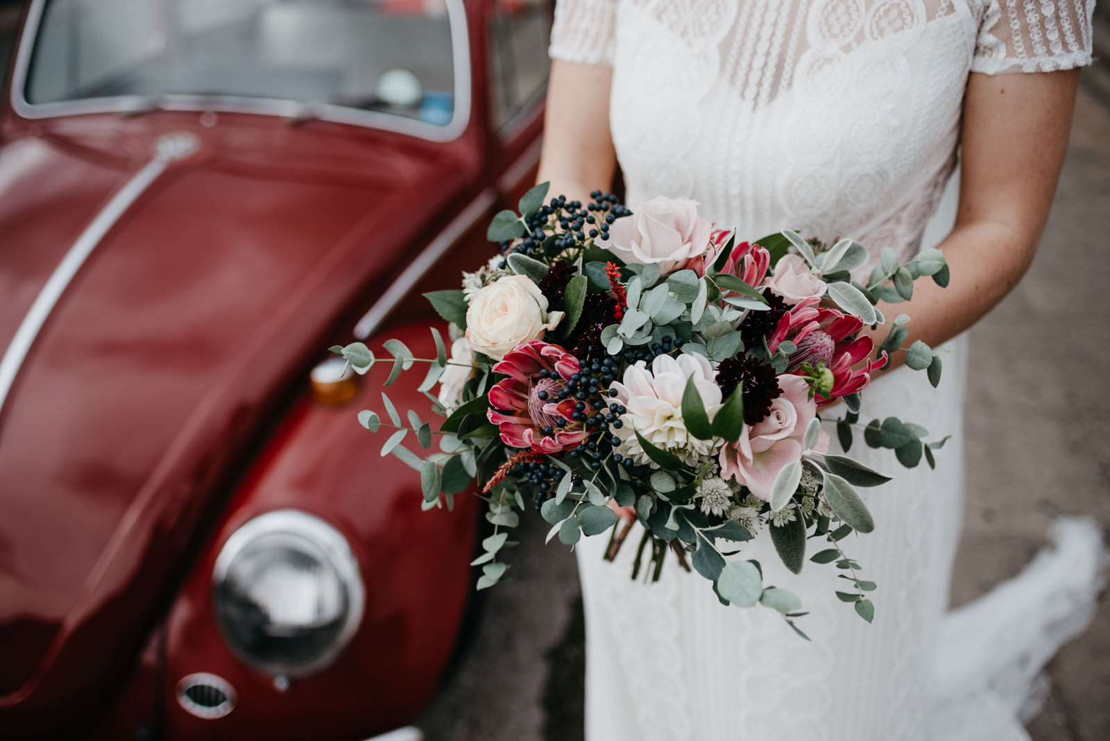 detail photograph of brides bouquet while she stands next to class VW Beetle at Bodnant Food Centre Wedding in Wales