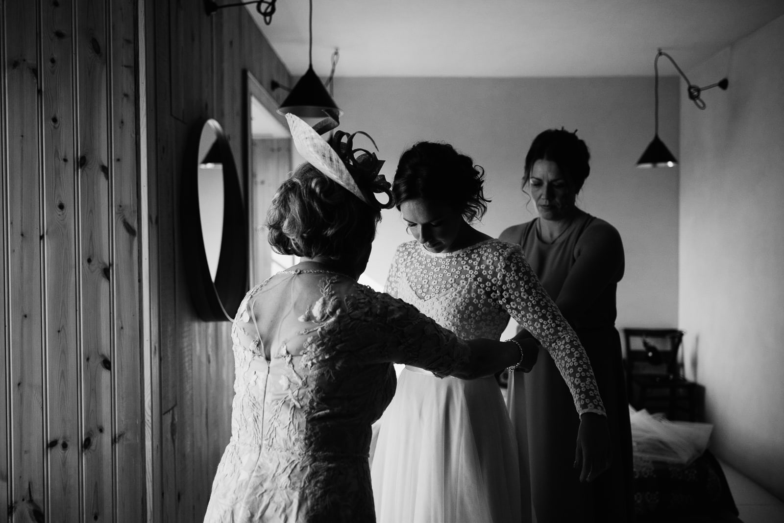 Mother of the bride helps fasten brides E&W Couture dress in the Lodge at Fforest Farm