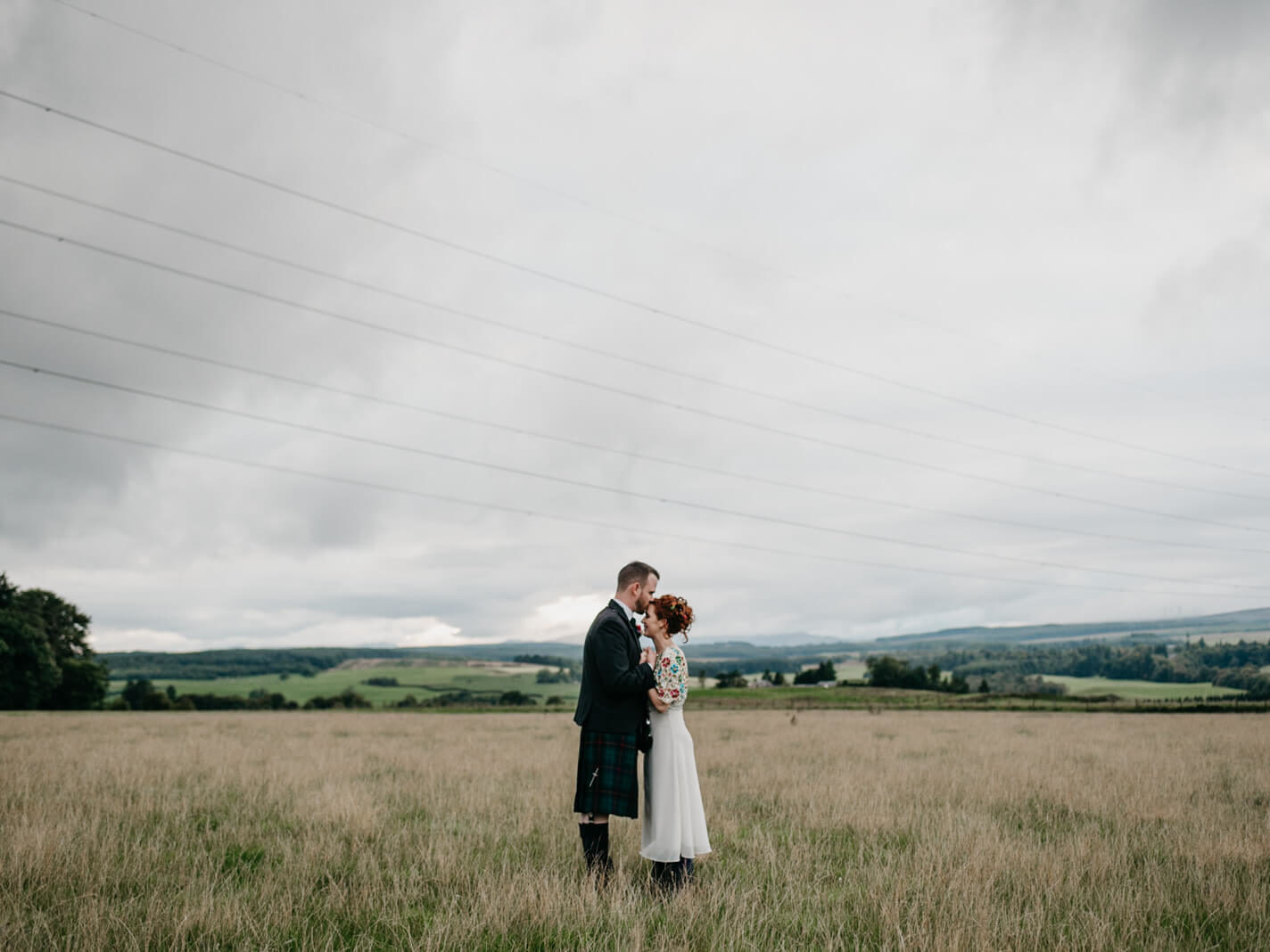 Bride and groom kiss in afield at their Farm Wedding in Dunblane