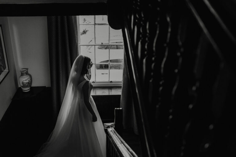 Black and white portrait of bride walking down the stairs at Plas Pantyderi Manor, a grade II listed Georgian wedding venue near Boncath.