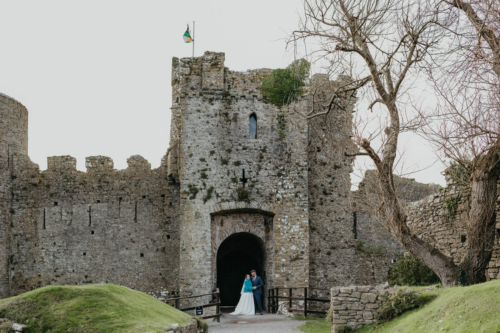 wedding couple stop for a photo at Manorbier Castle in Pembbrokeshire