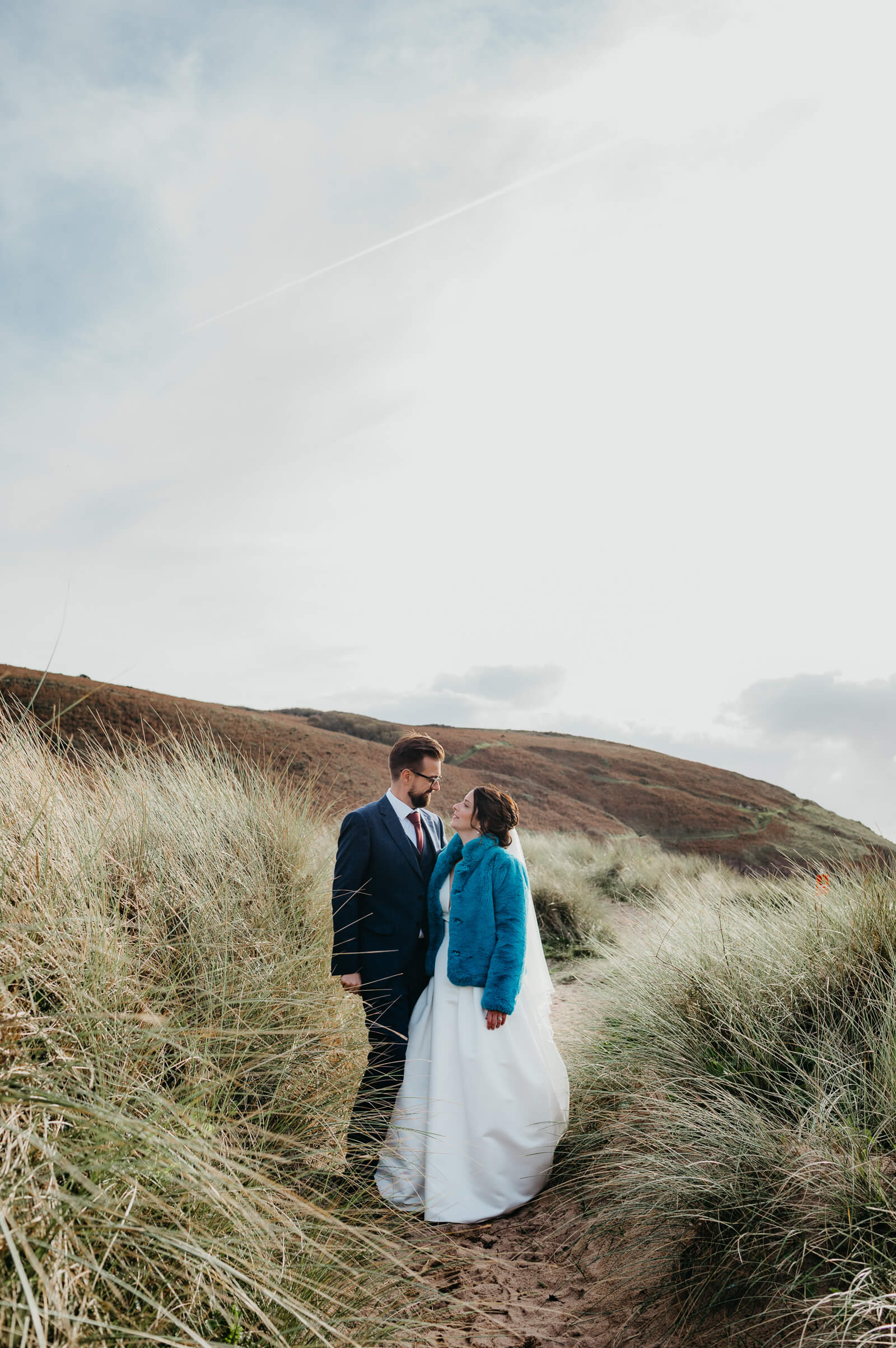 bride and group stop for wedding portraits on Pembrokeshire Coastal Path at Manorbier Beach