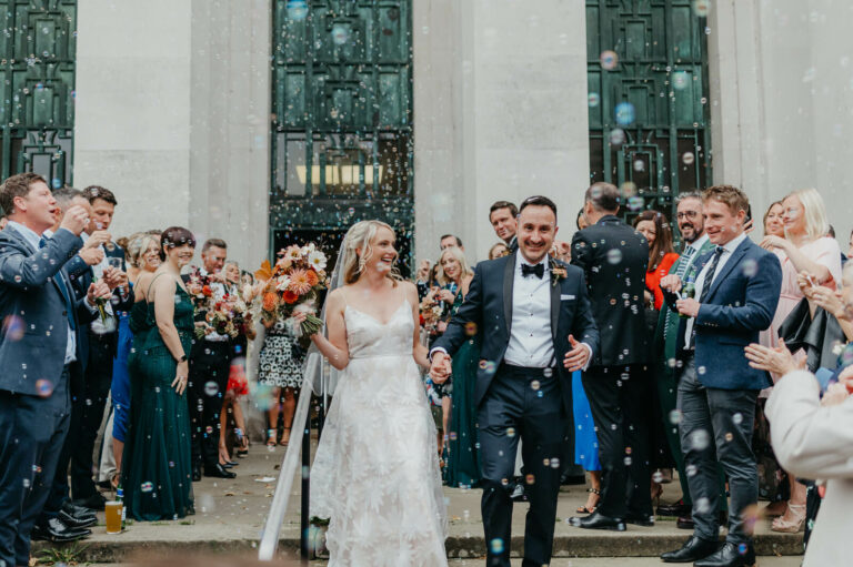 Overjoyed bride and groom celebrate with confetti outside Temple of Peace in Cardiff wedding venue.
